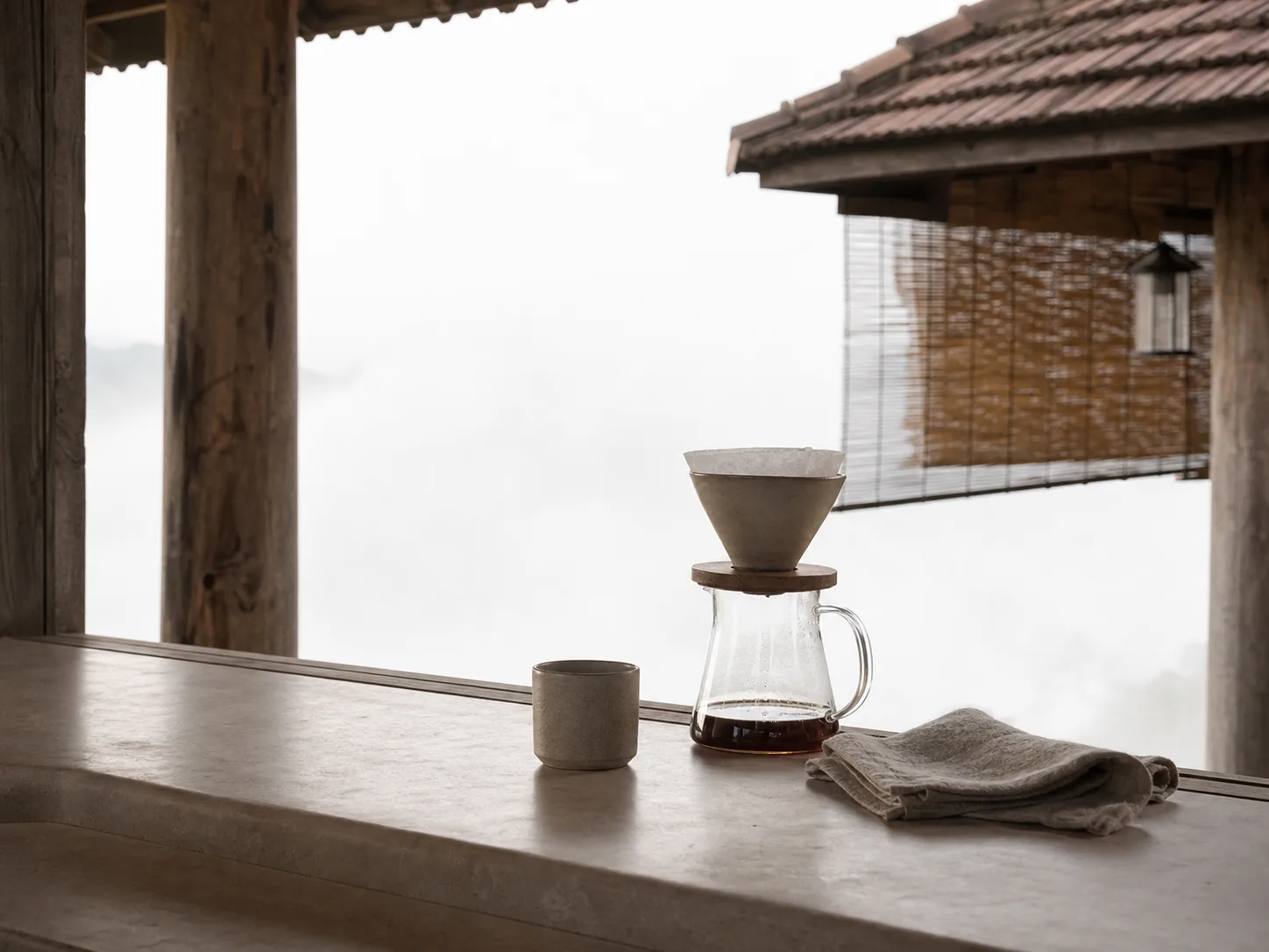 Pour-over setup on a pale stone counter beside a window full of white fog